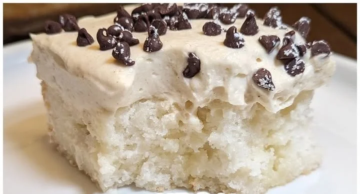 Delicious Cannoli Poke Cake topped with cream and chocolate chips.