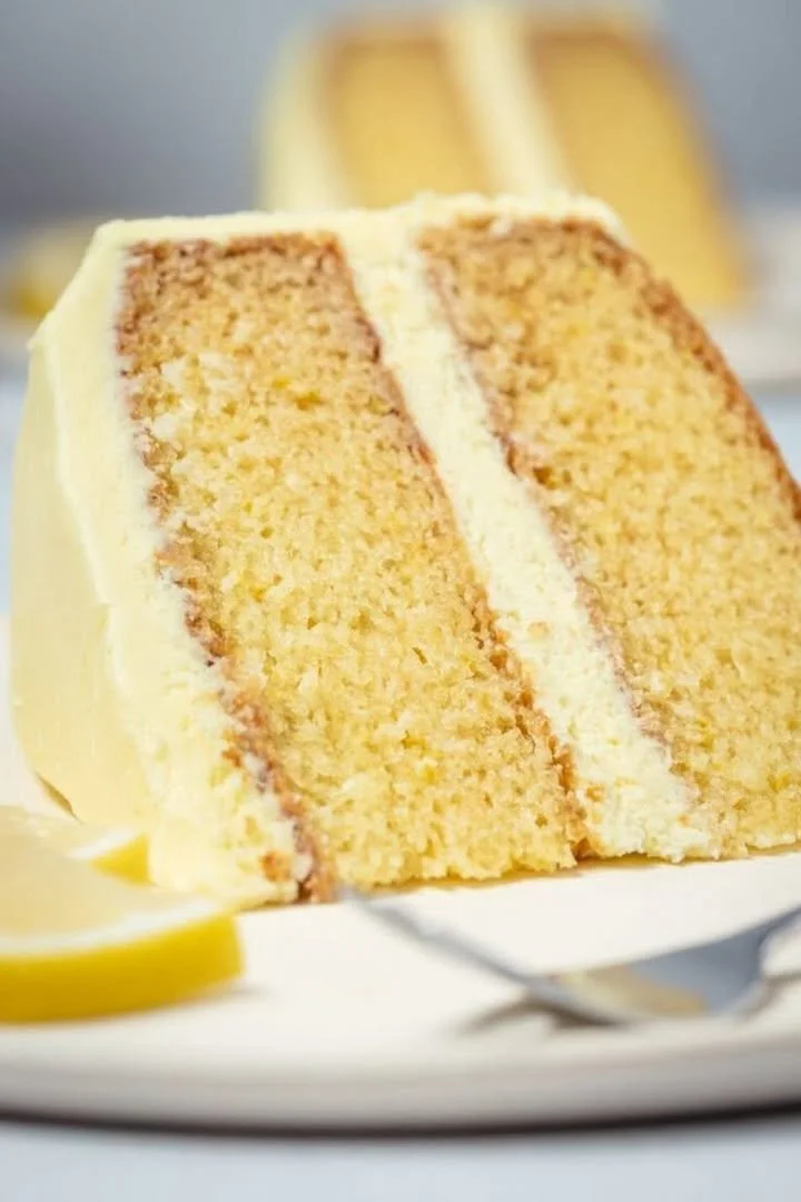 Delicious eggless lemon cake topped with fresh lemon zest and slices.