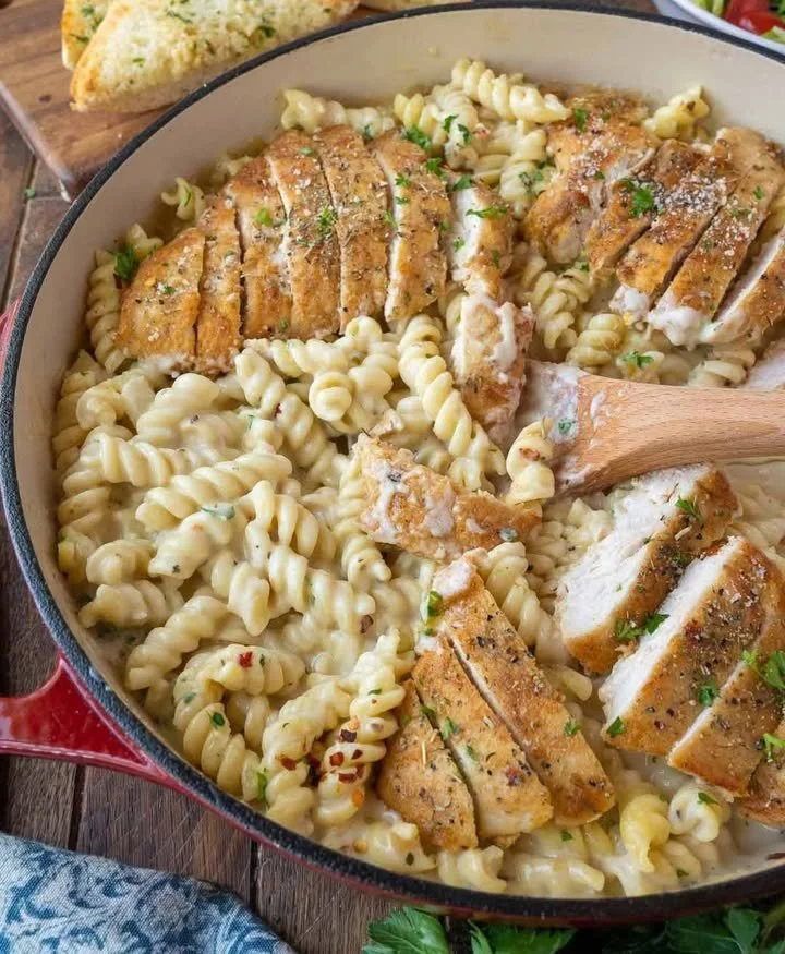 Creamy chicken pasta dish garnished with herbs and served in a bowl.