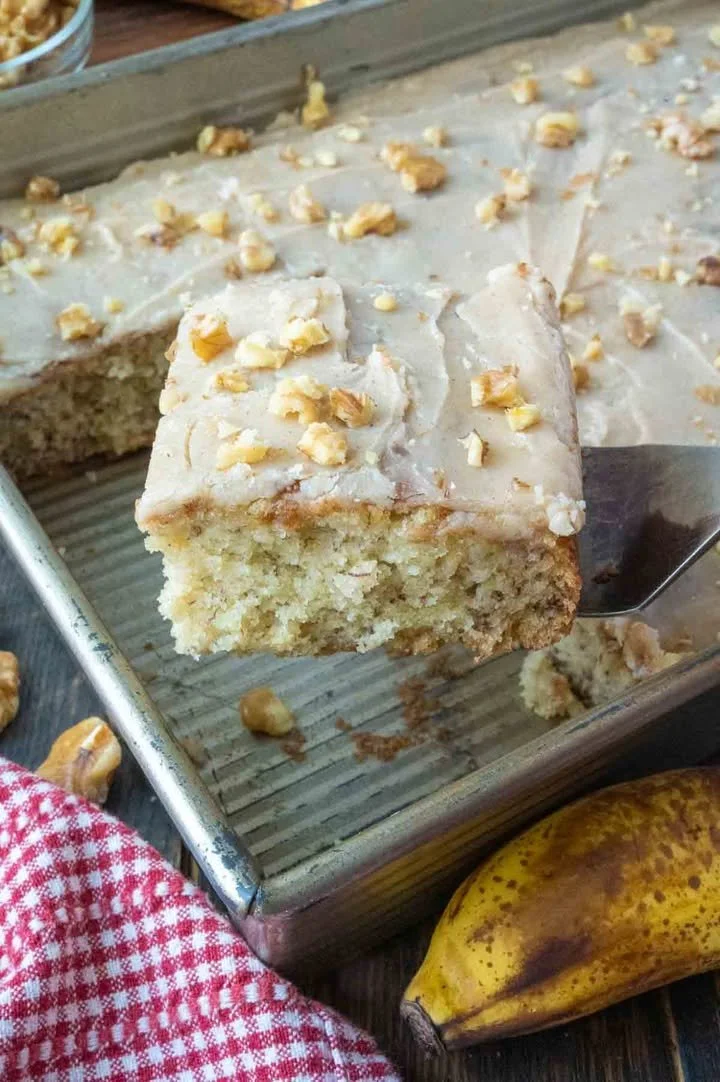 Delicious banana cake with brown butter frosting served on a white plate.