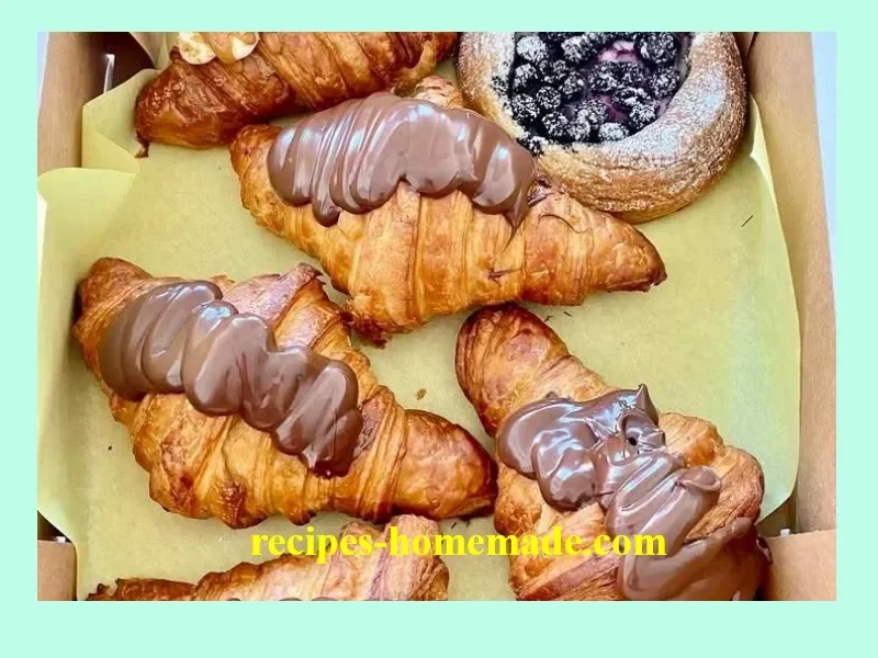 Freshly baked croissants on a wooden table, showcasing flaky layers and golden crust