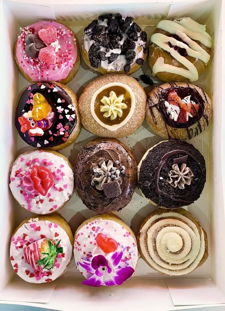 A variety of colorful glazed donuts on a display table