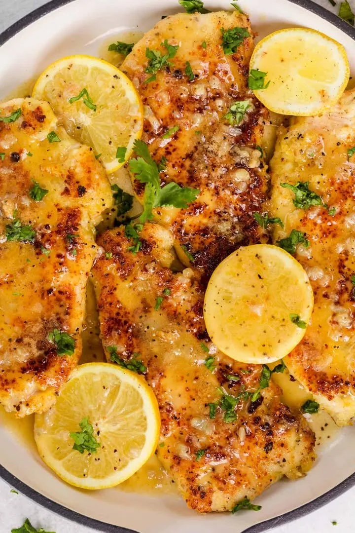 Parmesan-Crusted Chicken with lemon, garnished with herbs on a plate