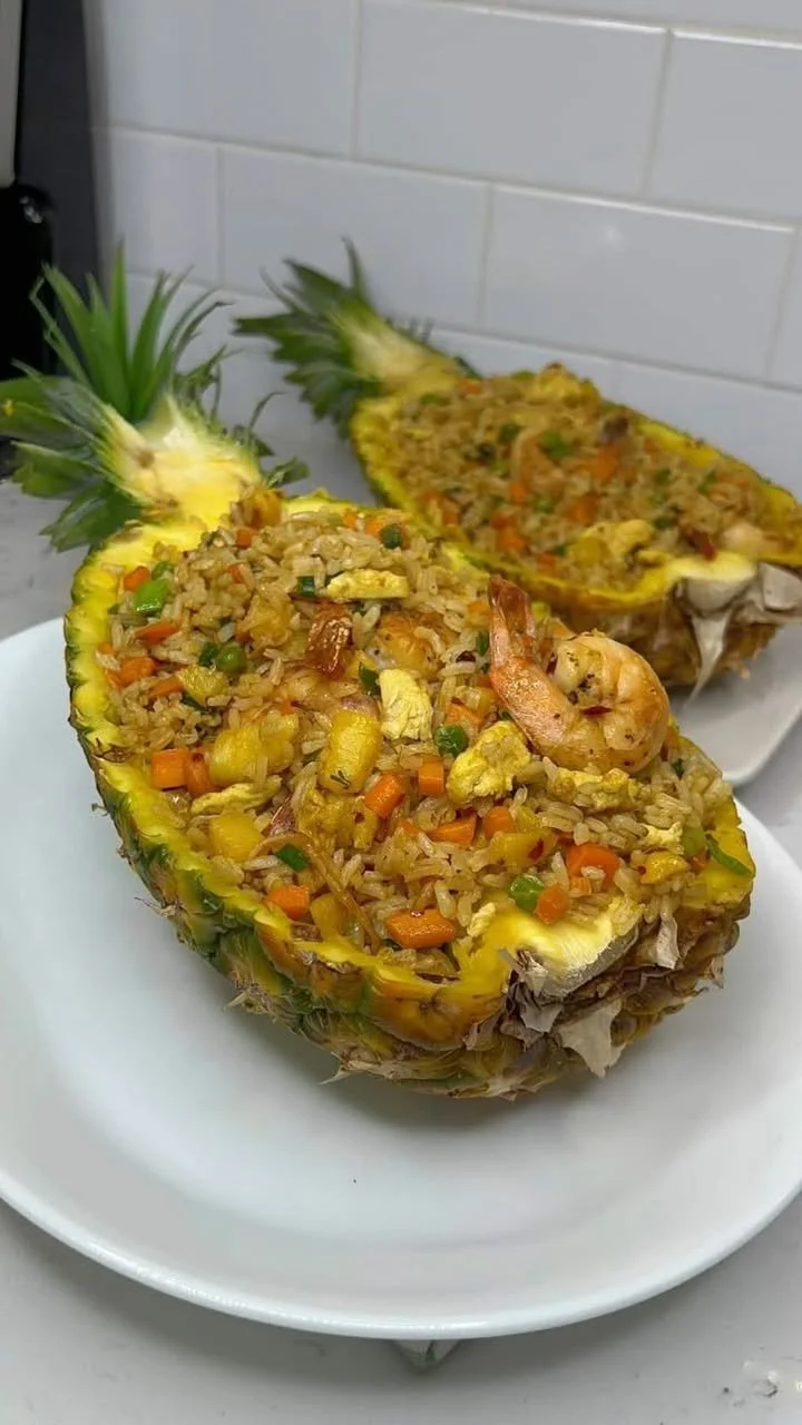 A bowl of colorful pineapple fried rice garnished with fresh herbs and vegetables