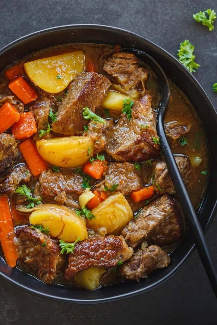 Slow cooker beef stew with vegetables and herbs served in a bowl