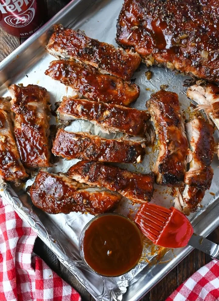 Slow Cooker Dr Pepper Ribs served on a plate with sauce and herbs