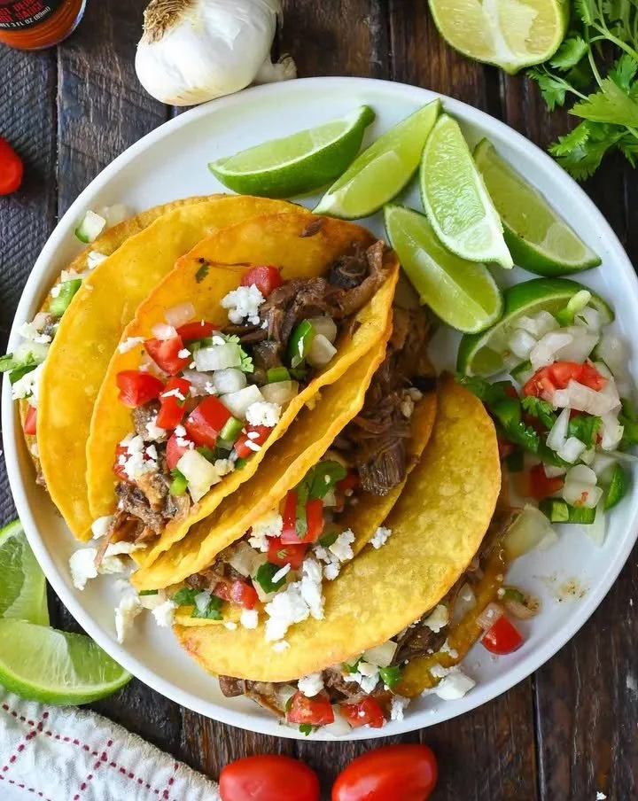 Delicious slow cooker short rib tacos served on a plate with fresh toppings.