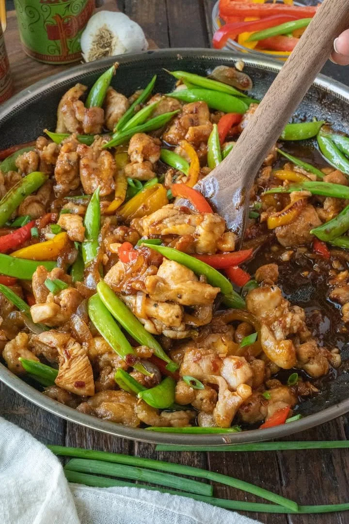 Spicy chicken stir fry with colorful vegetables in a skillet