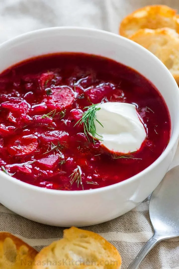 A bowl of traditional Ukrainian Borscht garnished with sour cream and herbs.