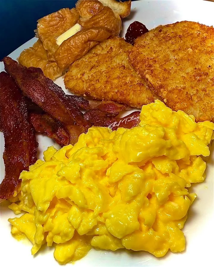 A plate of breakfast for dinner with eggs, pancakes, and bacon.