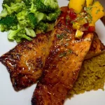 Broiled honey garlic butter salmon served with mango salsa on a plate.