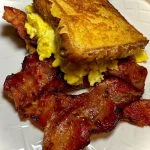 Cinnamon French Toast Breakfast Sandwich with syrup and fruit on a plate