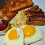 Cinnamon toast topped with sausage and sunny side up eggs