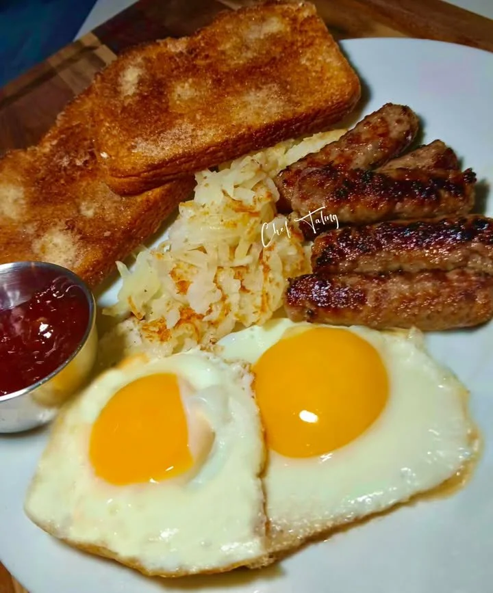 Cinnamon toast topped with sausage and sunny side up eggs