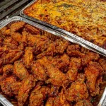 Plate of crispy Buffalo wings alongside cheesy baked ziti dish