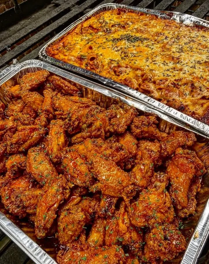 Plate of crispy Buffalo wings alongside cheesy baked ziti dish