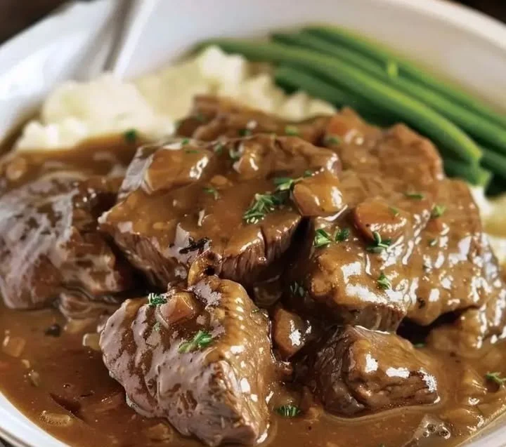 Crock Pot cubed steak served with gravy and vegetables in a rustic setting.
