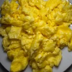Fluffy buttery scrambled eggs with cheese served on a plate
