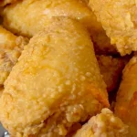 Plate of golden, crispy fried chicken served with sides.