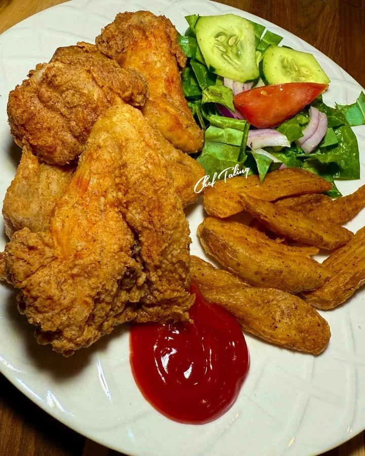 Delicious fried chicken with homemade potato wedges and a fresh salad on a plate
