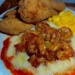Plate of crispy fried chicken with shrimp and honey butter grits