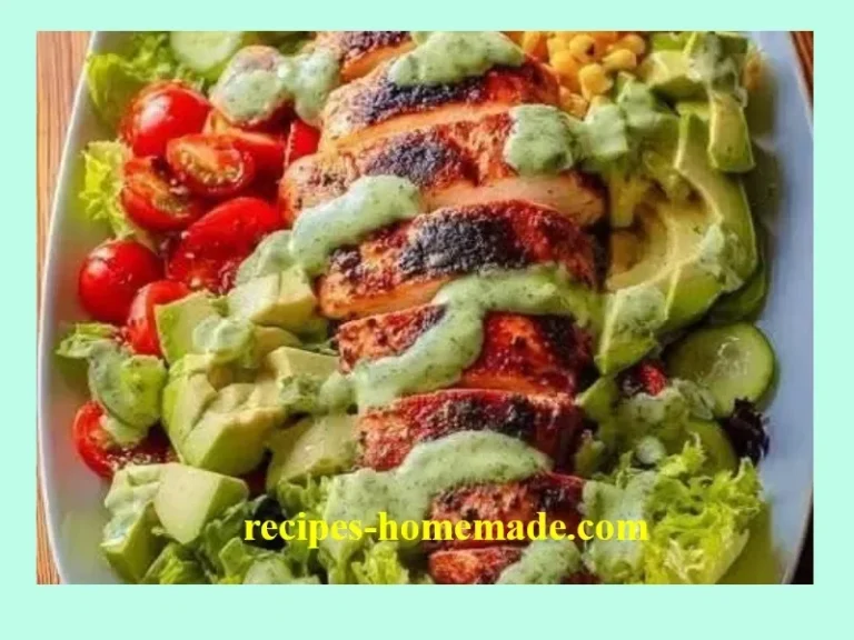 Grilled chicken salad topped with avocado and herb dressing on a wooden table.