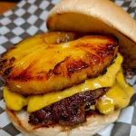 Grilled pineapple cheeseburger with cheese melting over a juicy patty
