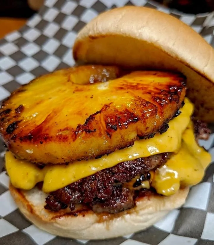 Grilled pineapple cheeseburger with cheese melting over a juicy patty