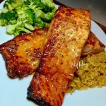 Honey Garlic Butter Glazed Salmon on a plate with herbs and lemon