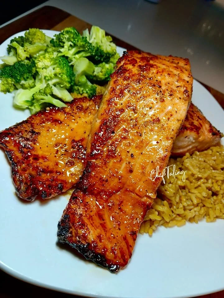 Honey Garlic Butter Glazed Salmon on a plate with herbs and lemon