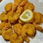 Lemon pepper fried shrimp served on a plate with a garnish of lemon slices