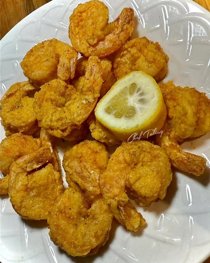 Lemon pepper fried shrimp served on a plate with a garnish of lemon slices