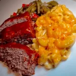 Delicious meatloaf served with quick mac and green beans on a plate
