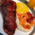 Plate of medium well steak served with shrimp and grits