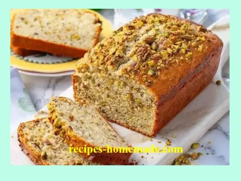 Freshly baked pistachio bread with nuts on a wooden cutting board.