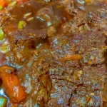 Delicious pot roast served with vegetables and gravy on a dinner plate