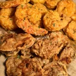 Plate of shrimp and oysters served with lemon and cocktail sauce.
