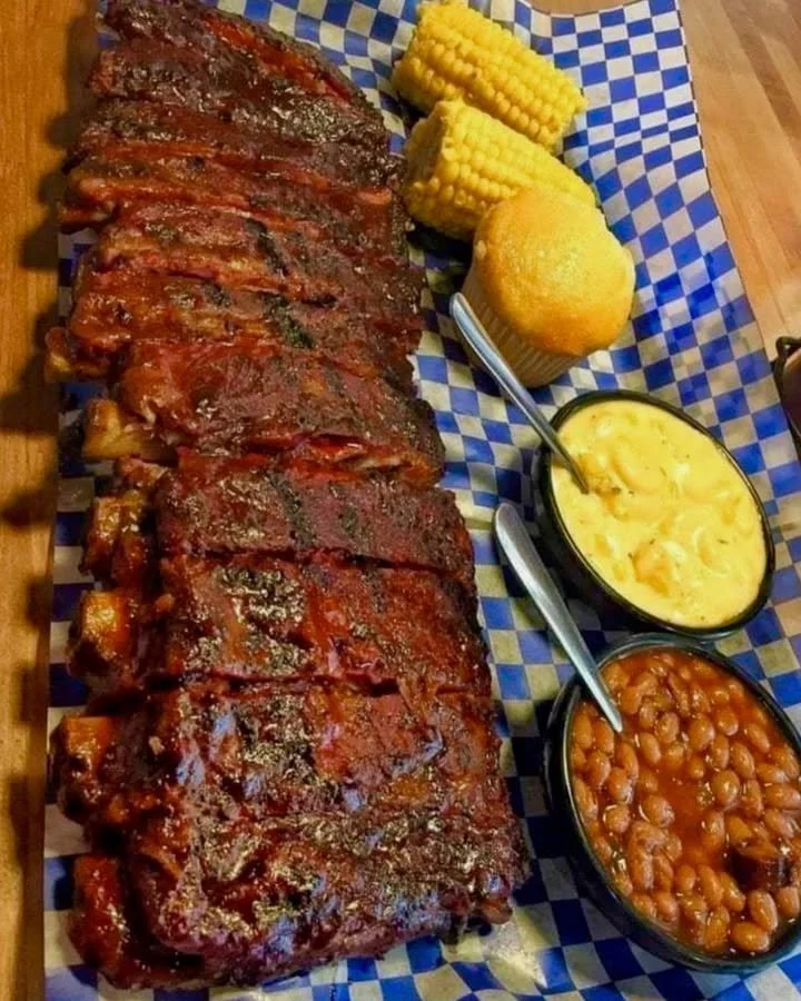 Delicious smoked barbecue ribs served on a rustic wooden platter.