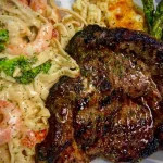 Delicious Steak and Shrimp Alfredo with creamy sauce and garnishes