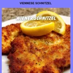 Plate of traditional Viennese Schnitzel served with lemon and parsley garnish.