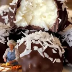 Delicious no bake coconut cream balls on a white plate garnished with coconut flakes.