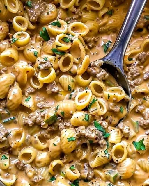 Creamy Cheddar Beef Pasta in a bowl with fresh herbs and cheese