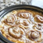 Crock-Pot cinnamon roll casserole fresh out of the slow cooker with icing
