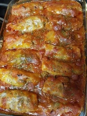 Plate of stuffed cabbage rolls filled with rice and meat in tomato sauce.